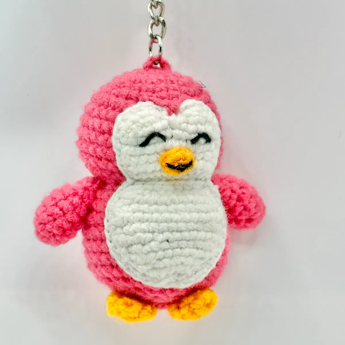 Smiling pink crochet penguin charm with a white belly