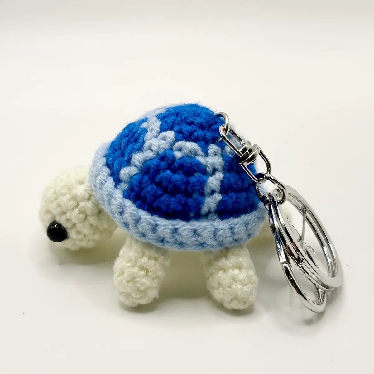 Crochet turtle charm with an ocean blue shell on a silver clasp