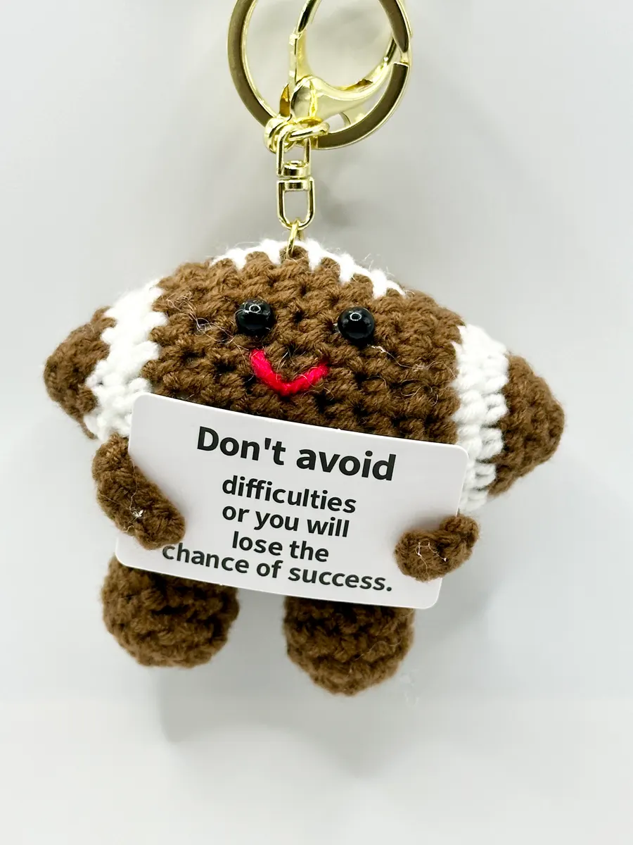 Brown crochet football keychain holding a positive message card