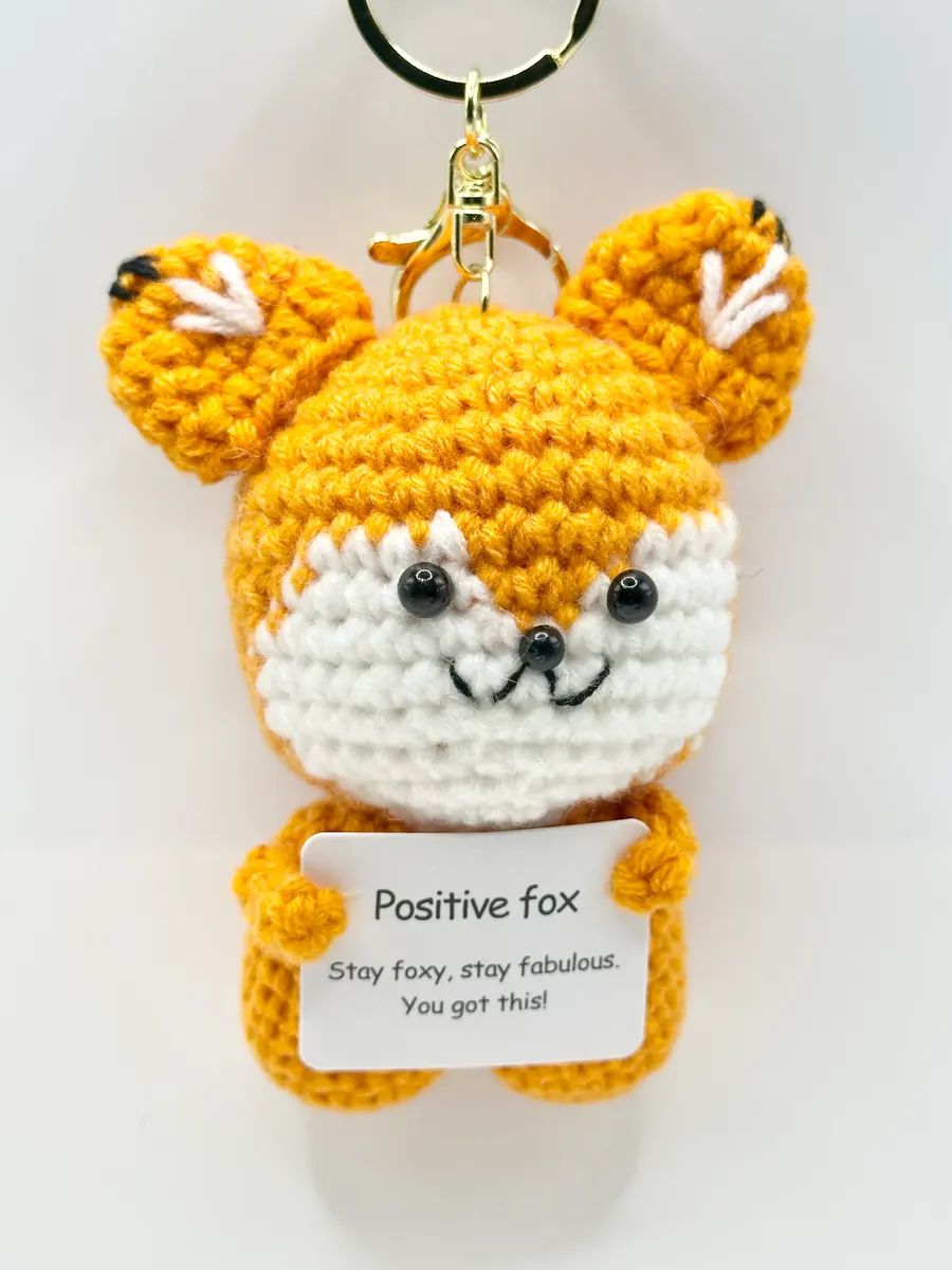 Orange crochet fox keychain holding a Positive fox card