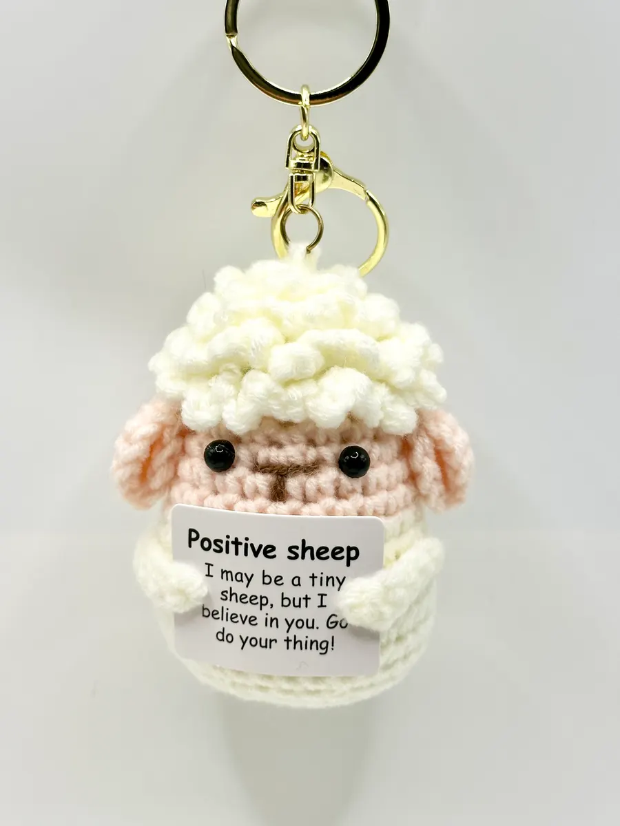 Cream crochet sheep keychain holding a Positive sheep card