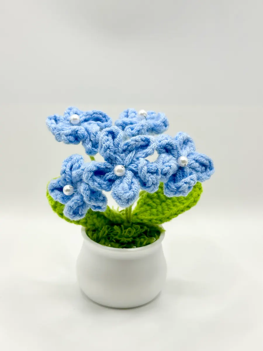 Blue crochet five-petal blossoms with pearl centers in a small white pot